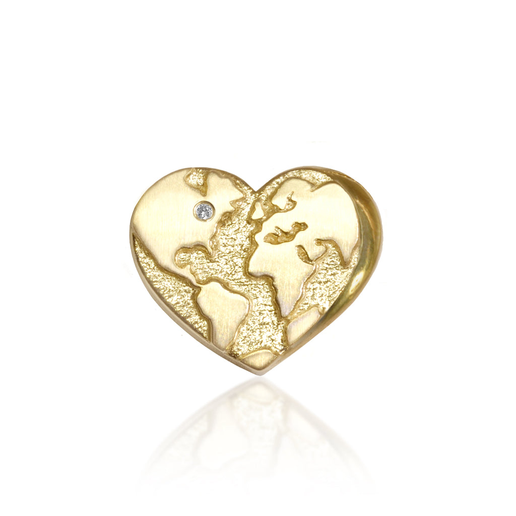 A gold charm in the shape of a heart with a world map design and a sparkling diamond on it, displayed against a white background.